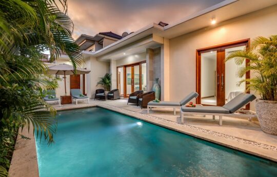 Swimming Pool with villa exterior views and day beds at dusk