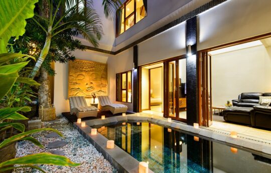 Swimming pool at night with lights on and villa exterior