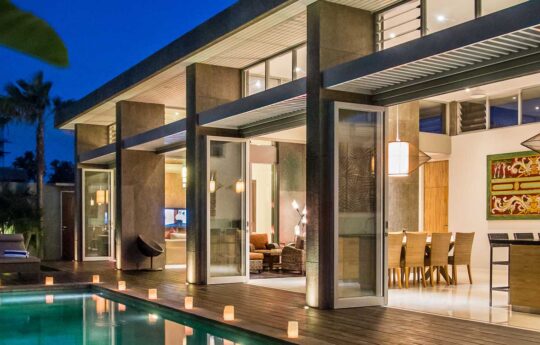 Exterior view of Villa Damai at night with pool lights on