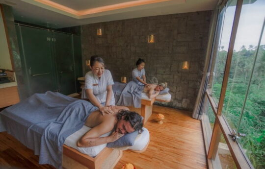 Couple in a day spas laying down on bed having massage