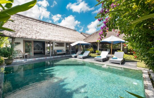 Sunny pool views of Villa Damai Manis with day beds and alang alang roof