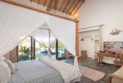 Modern bedroom in villa with TV and views of pool