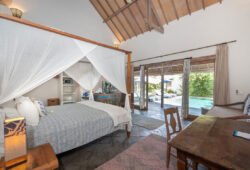 Modern bedroom with bed and views of swimming pool and garden