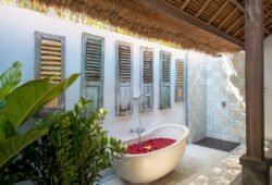 Rustic outdoor bathroom with bathtub full of petals