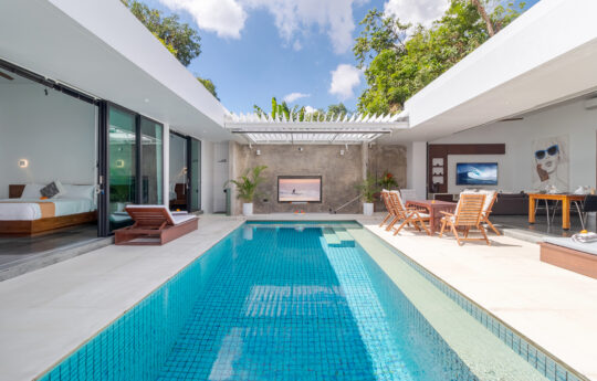 large sunny swimming pool with modern villa exteriors and day beds