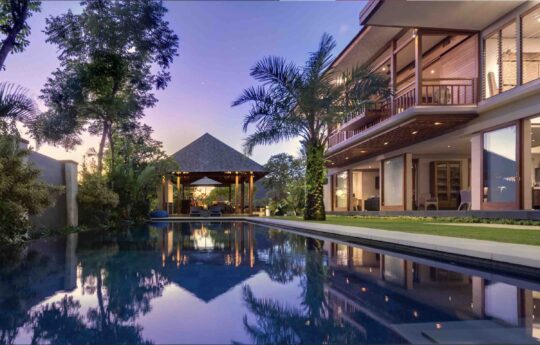 two level villa exterior with swimming pool view at dusk