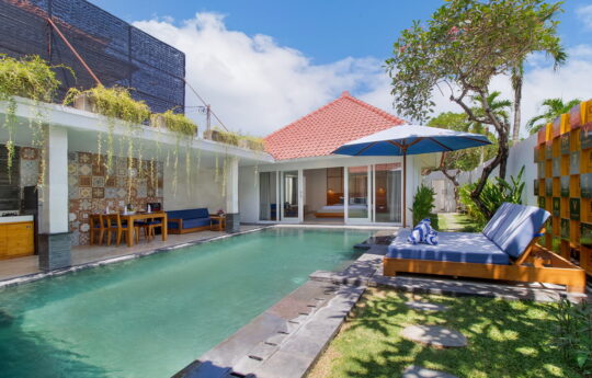 Swimming pool, day beds and villa living areas on sunny day