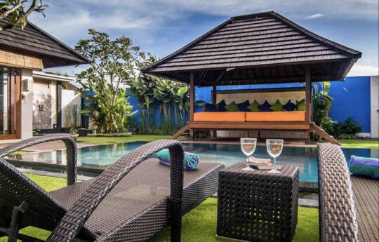 Day beds by the pool with 2 champagne glasses and view of pool of Villa Bon Bon