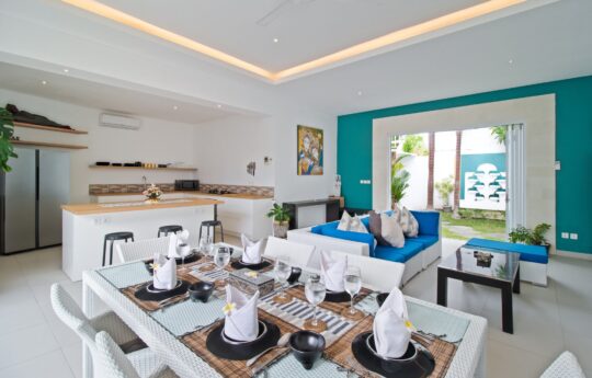 Dining table and lounge area of villa with kitchen