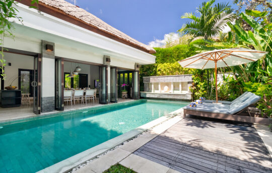 Sunbeds by the pool during daytime with Villa Jepun's interiors in background
