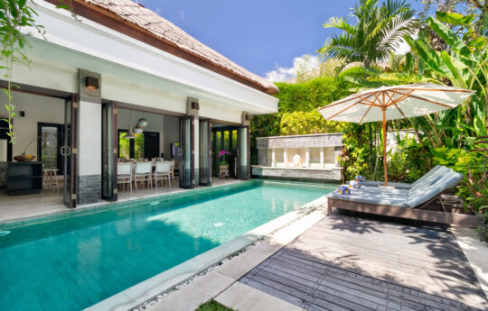 Sunbeds by the pool during daytime with Villa Jepun's interiors in background