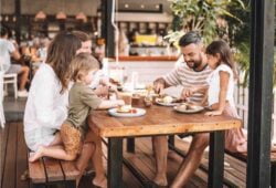 Young family of four (parents and young boy and girl) sitting down at table having lunch